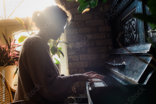 woman playing the old rustic piano with a beautiful ray of sunlight from behind, side view, romantic mood, soft light,  photo