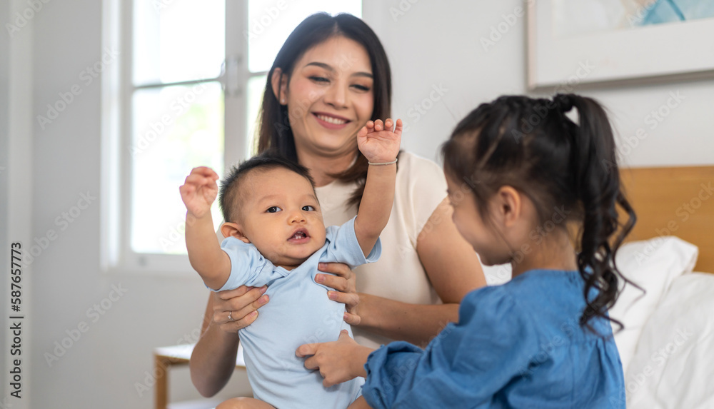 Portrait of enjoy happy love family asian mother playing with adorable little asian baby and sister girl, newborn, infant.Mom touching care with cute son in a white bedroom.Love of family concept Portrait of enjoy happy love family asian mother playing with adorable little asian baby and sister girl, newborn, infant.Mom touching care with cute son in a white bedroom.Love of family concept