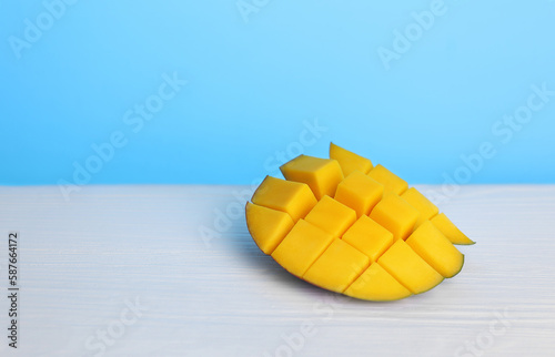sliced, juicy mango on a light wooden table and a blue background. Selective focus
