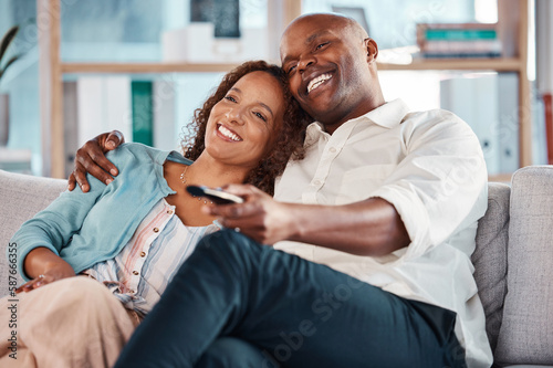 Couple, watching tv and smile on sofa in home living room, bonding and cuddle. Interracial, television and happiness of black man and mature woman relaxing while streaming movie, film or video online
