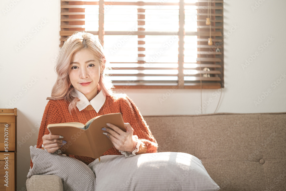 Portrait of asian woman reading a book in living room. Drinking a hot coffee or cocoa at morning. Portrait of asian woman reading a book in living room. Drinking a hot coffee or cocoa at morning.