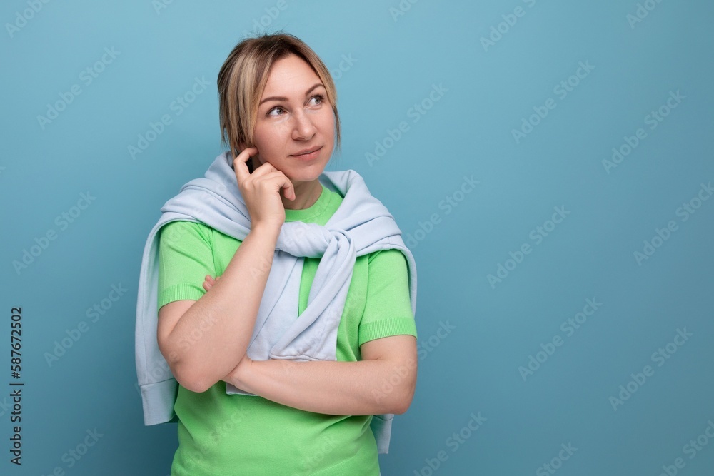 horizontal photo of a blond attractive girl pensive in a casual outfit on a studio blue background with copy space horizontal photo of a blond attractive girl pensive in a casual outfit on a studio blue background with copy space