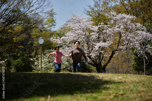 春の桜満開の公園で遊んでいる子供姉妹の様子
