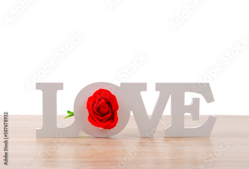 The wooden letters LOVE word with red rose flower on wooden table.