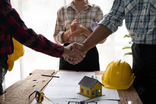 Architect and engineer construction workers shaking hands while working for teamwork.