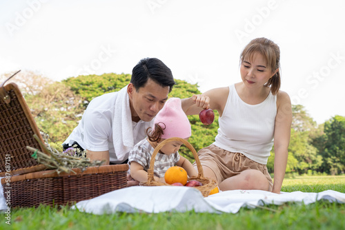 Asian family, Dad, Mom and Infant (baby girl) picnicking in city park, happy healthy in the holiday vacation summer.