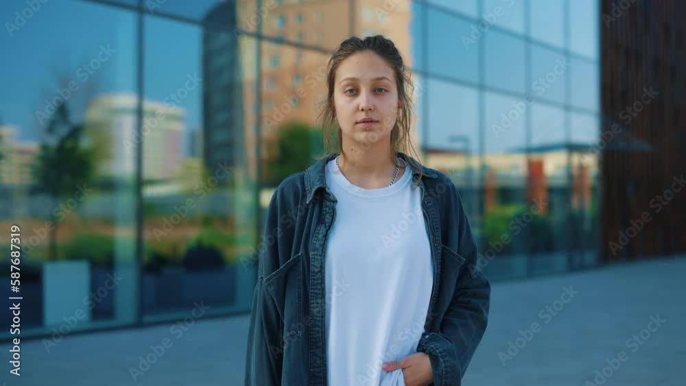 Portrait of the Attractive Young Woman with Piercing Looking at the Camera, Posing Standing Outside near Office Centre. Wearing Casual Clothes Urban City Background. People Concept. Portrait of the Attractive Young Woman with Piercing Looking at the Camera, Posing Standing Outside near Office Centre. Wearing Casual Clothes Urban City Background. People Concept.