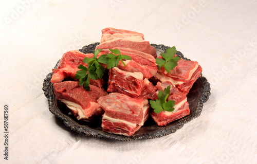 Raw beef ribs on a metal plate, white background