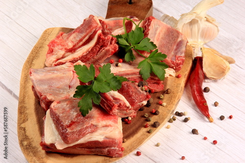 Raw beef ribs on wooden kitchen board, white background