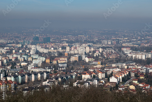 Cityscape of Banja Luka during sunny day, distant hill barely visible in hazy polluted air