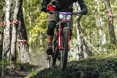 athlete rider on downhill bike riding forest trail, racing DH mountain bike, extreme summer sport games