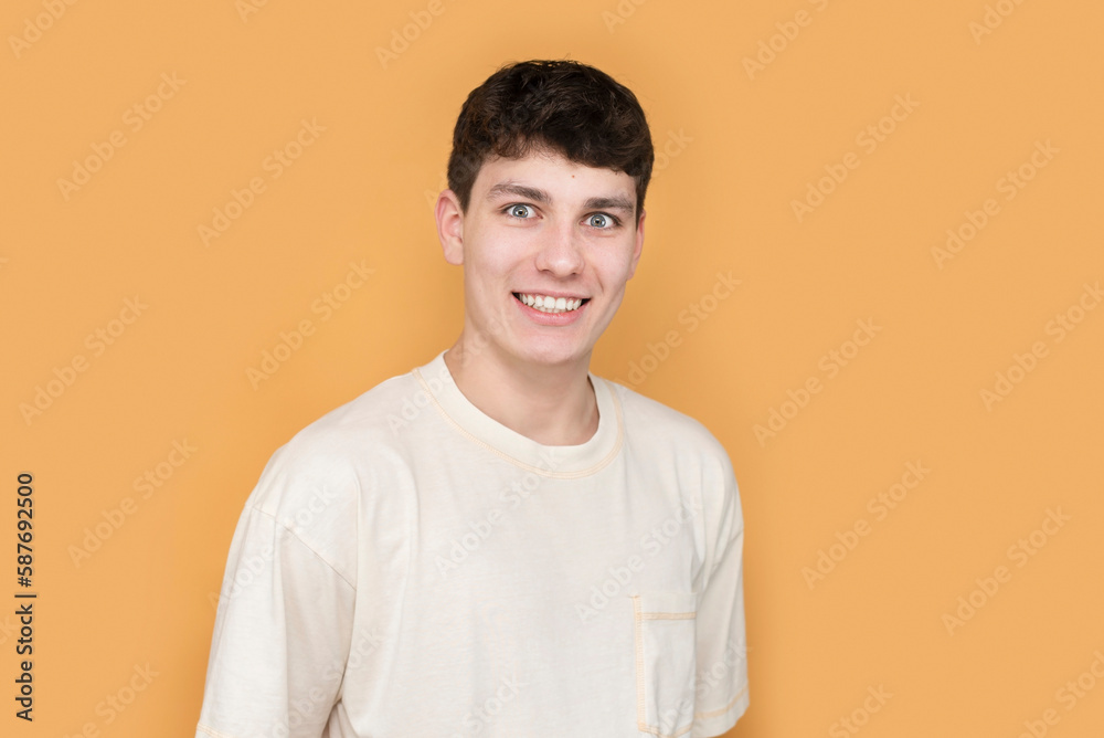 The boy is a teenager, the young man seems to be mocking someone, but with a positive smile, he laughs at himself, the boy has a funny, slightly silly look. Silly fooling grimacing boy