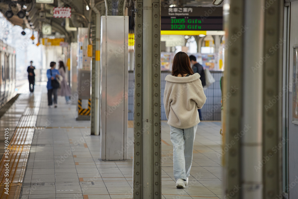 JR名古屋駅のホームで歩く若い女性乗客の後ろ姿と電車の風景