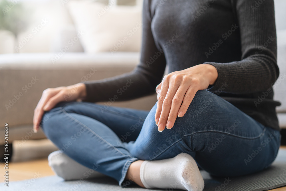 Young woman sitting on the floor and doing meditation practice mindfulness at home