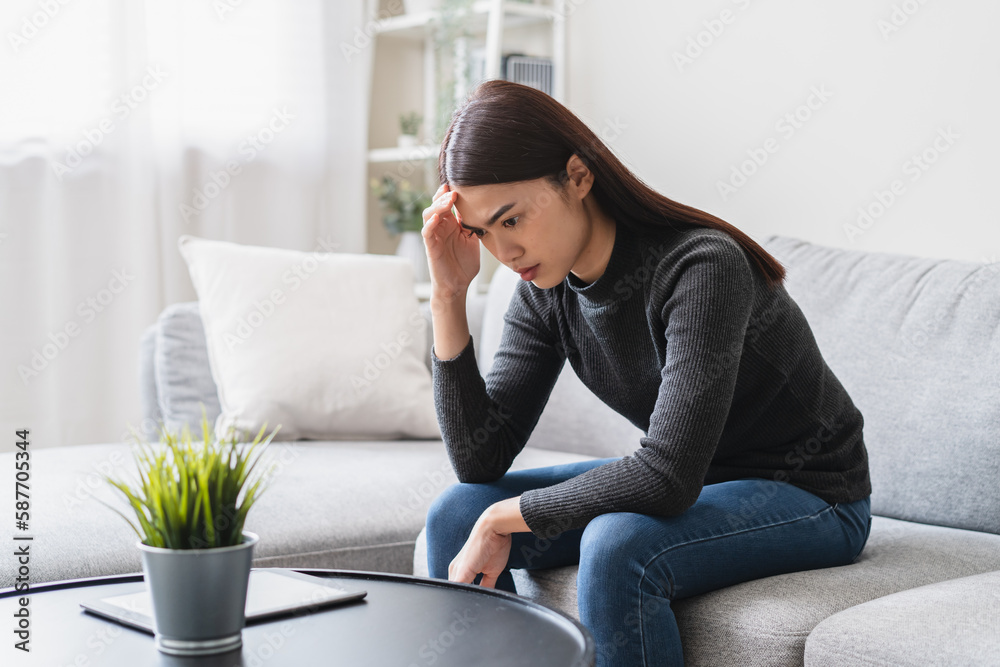 Unhappy anxiety young Asian woman sitting on the sofa at home. Unhappy anxiety young Asian woman sitting on the sofa at home.