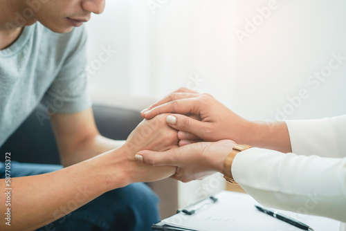 Woman holding hands of the stressed man about mental health problem © Pormezz