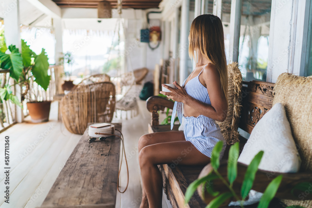 Unrecognizable woman sitting on bench and drinking coffee in cafe Unrecognizable woman sitting on bench and drinking coffee in cafe