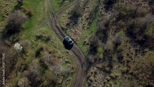 Aerial top view of grey car drives alone off-road on dirty rural roads filming by drone.
