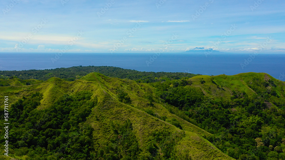 Aerial view of mountains and hills with rainforest and green grass under a blue sky with clouds on a Sunny summer day. Bohol, Philippines. Aerial view of mountains and hills with rainforest and green grass under a blue sky with clouds on a Sunny summer day. Bohol, Philippines.