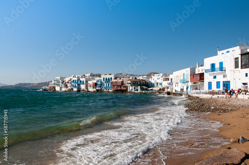 View from the beach the white seaside houses of the village of Chora on the island of Mykonos in Greece. In the background the blue sky during summer vacation.