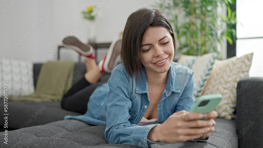 Young caucasian woman using smartphone lying on sofa at home Young caucasian woman using smartphone lying on sofa at home