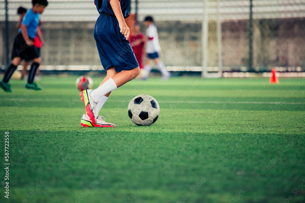 Children playing control soccer ball tactics cone on a grass field with for training background