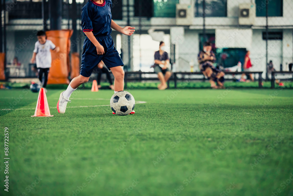 Children playing control soccer ball tactics cone on a grass field with for training background