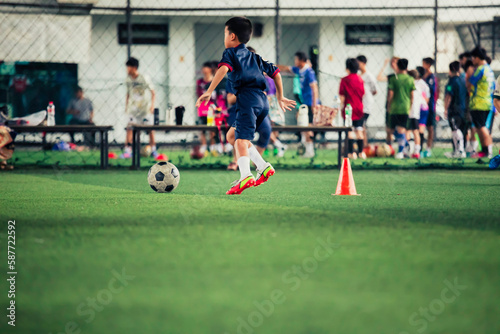 Children playing control soccer ball tactics cone on a grass field with for training background © chitsanupong
