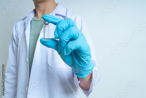 Doctor, infectionist or scientist wearing medical gloves is holding coronavirus vaccine for against, prevention coronavirus, covid-19 on white background and copy space. Covid-19 vaccine concept. photo