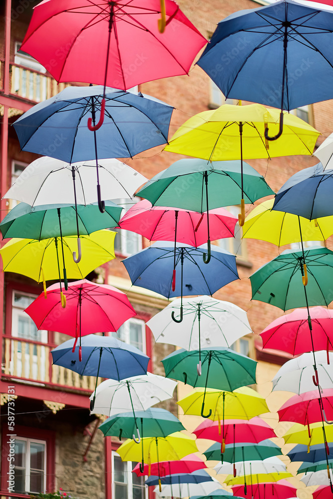 Variety of yellow, red, blue, pink and white umbrellas hanging above a street in Quebec, Canada