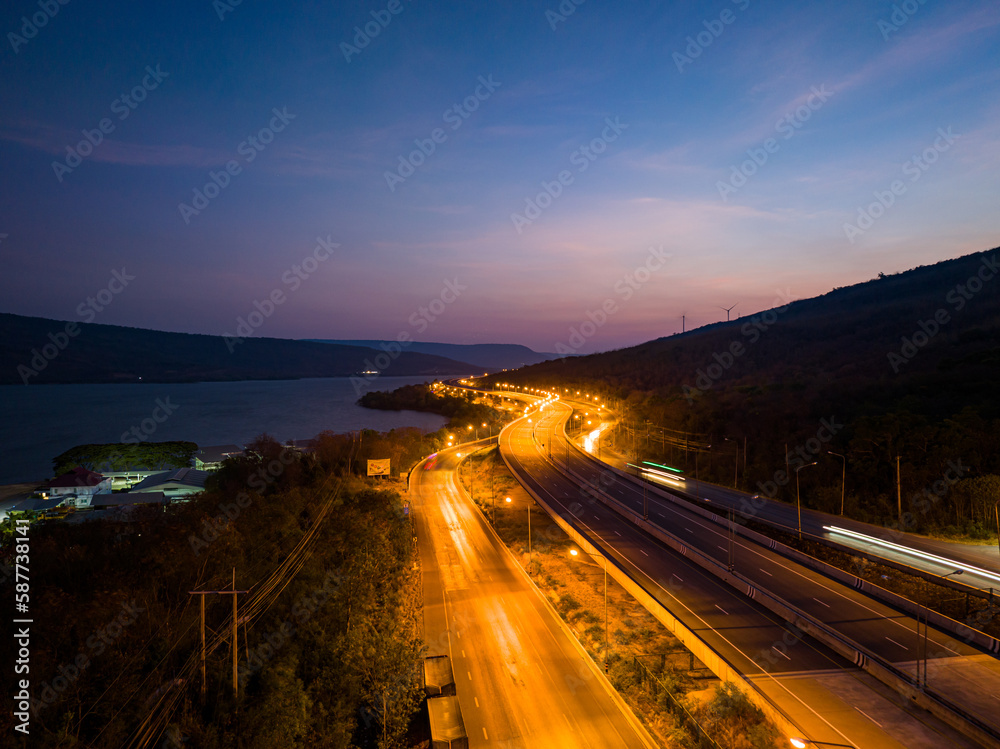 aerial view orange lights on the expressway along the route along the Lam Ta Khong Dam..beautiful scenery in the early morning .wind mill on the mountains, rivers and sweet skies background.