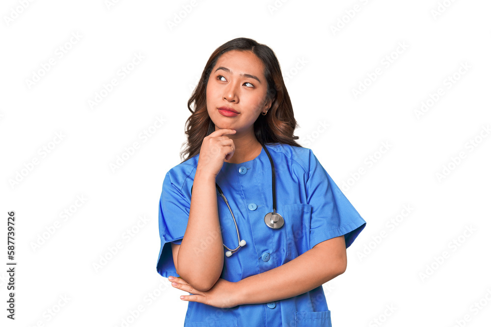 A young nurse chinese woman looking sideways with doubtful and skeptical expression. A young nurse chinese woman looking sideways with doubtful and skeptical expression.