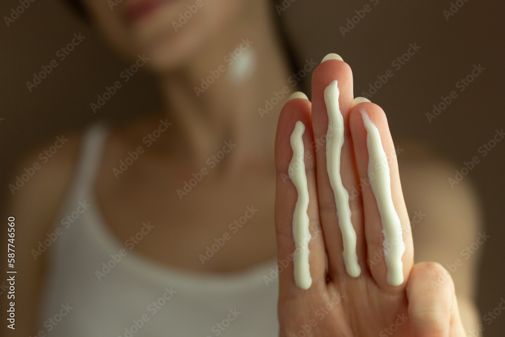 A person applying the correct amount of sunscreen for face and neck (three finger lengths).