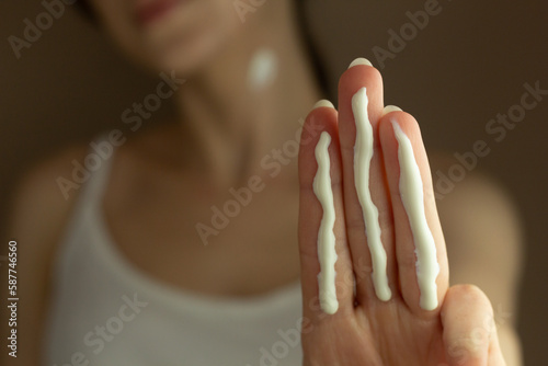 A person applying the correct amount of sunscreen for face and neck (three finger lengths).