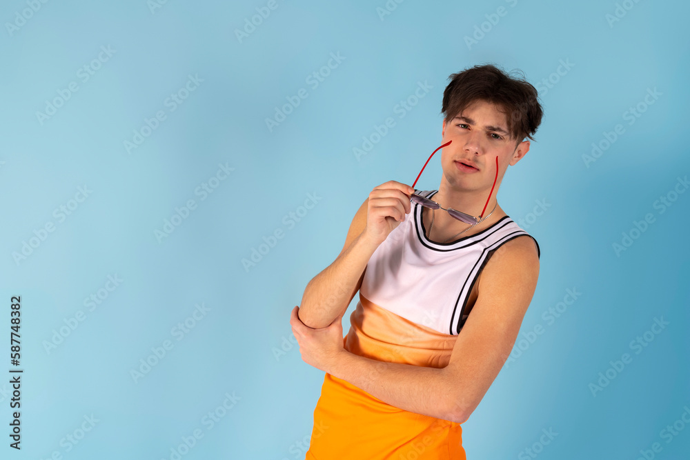 Photo of young man fooling around. using fruits instead of eyes. Sunglass, shirt, shorts, isolated blue color. Photo of young man fooling around. using fruits instead of eyes. Sunglass, shirt, shorts, isolated blue color.
