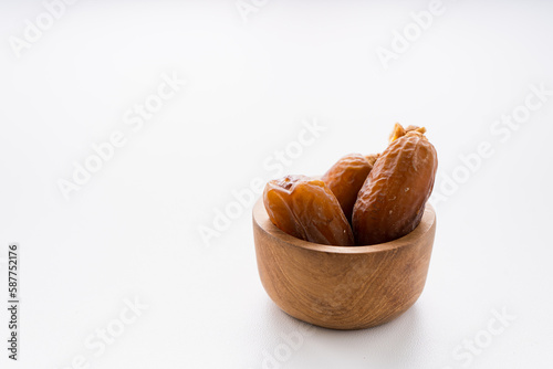 Dried dates fruit in wooden mini bowl isolated on white background. 
