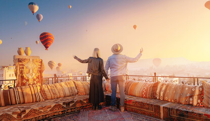 Happy lover couple man and women on rooftop of cave house enjoying of Goreme city panorama, Cappadocia Turkey travel