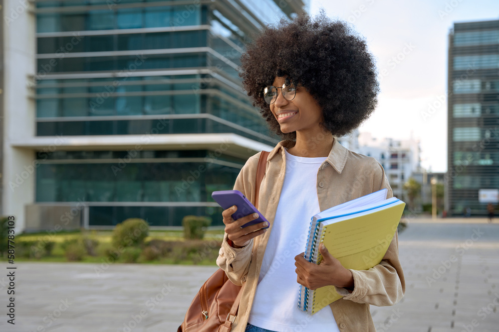 Happy African American student girl with afro haircut enjoy online communication, hold exercise books and backpack, scroll social media app on cell phone device, looking at camera on city street. Happy African American student girl with afro haircut enjoy online communication, hold exercise books and backpack, scroll social media app on cell phone device, looking at camera on city street.