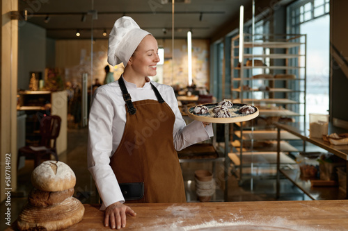 Tableau sur toile Pastry chef presenting freshly baked cookies standing at bakery kitchen