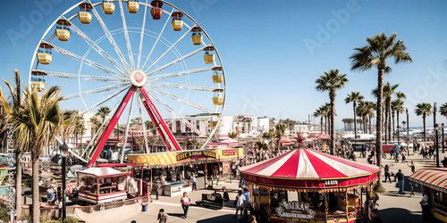 A mesmerizing Ferris wheel looms over the Santa Monica pier, captivating onlookers with its bright colors and majestic presence. - generative ai