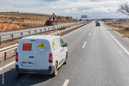 Van with orange plates of dangerous goods and with danger tags by radioactivity, circulating on the highway.