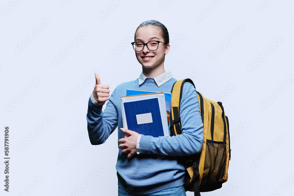 Teen girl student showing thumb up positive like symbol on white background Teen girl student showing thumb up positive like symbol on white background
