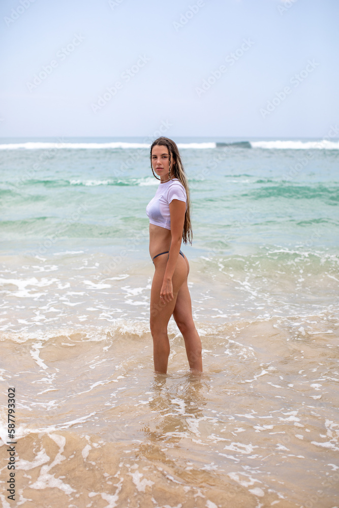 Slim young woman walks into the ocean. Slim young woman walks into the ocean.