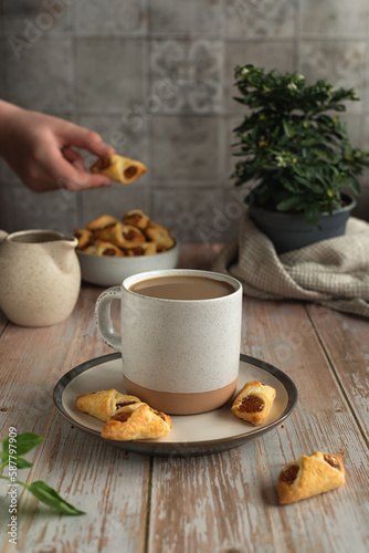 Spring still life on the kitchen table. Ceramic cup of coffee and bowl with homemade puff pastry on a wooden table. Concept for wishing good morning.