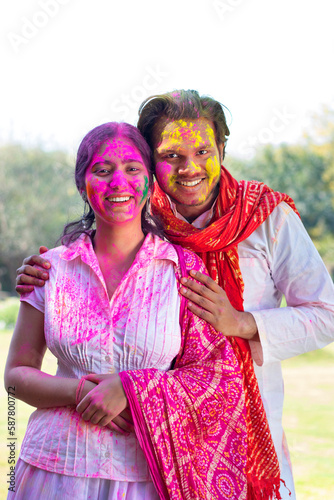 portrait of smiling young couple with colourful face and sunglass on Holi