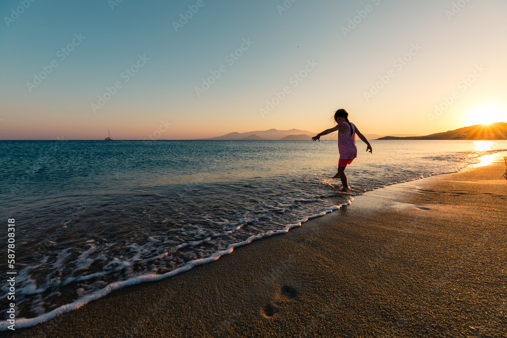 Naxos, Grece - July 20, 2020 - Girl having fun at beach during sunset over Naxos Island