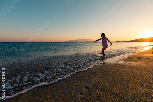 Naxos, Grece - July 20, 2020 - Girl having fun at beach during sunset over Naxos Island