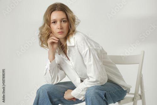 Fashion portrait of young woman in white cotton button down shirt and blue jeans on the white background