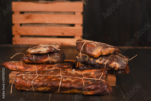 Dried Processed Beef Jerky tied with string on wooden board against black background.