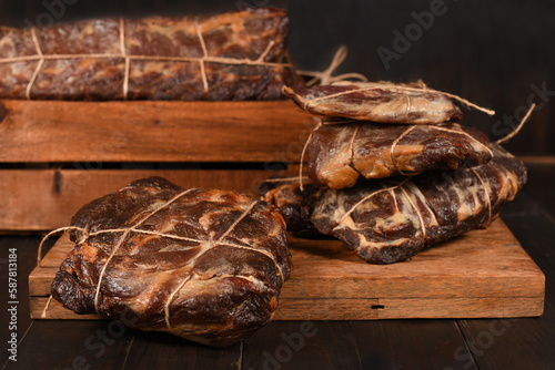 Dried Processed Beef Jerky tied with string on wooden board against black background.